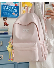 Detail of light pink nylon backpack featuring a white bow embroidery and moon plush charm