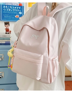 Detailed side view of pink school backpack with bow embroidery and moon charm