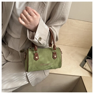 Close-up of green matte Boston bag featuring brown leather handles and gold metal logo