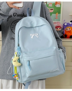 Detail of light blue backpack featuring white bow embroidery and a moon plush charm