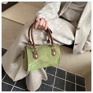 Detail of green suede Boston bag with brown leather handles and brand embroidery