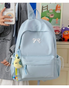 Detail of light blue nylon backpack with white bow embroidery and moon plush charm