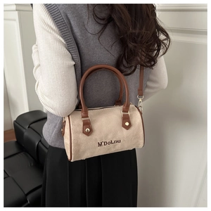 Detail of beige suede Boston bag with brown leather handles and brand embroidery