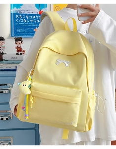 Detail of pale yellow waterproof backpack with bow embroidery and plush moon pendant
