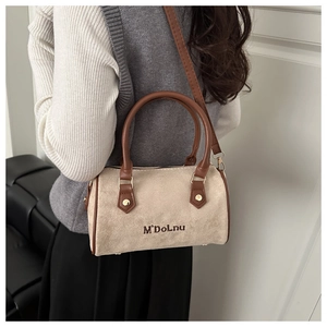 Detail of Boston handbag featuring beige suede fabric and brown leather trim accents