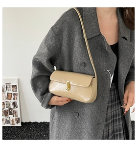 French style cream baguette bag with gold metal rotating buckle shown on shoulder