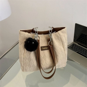 Borsa tote beige trapuntata con manici in pelle marrone e ciondolo di peluche per pendolari