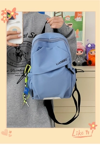 Détail d'un sac à dos en nylon bleu clair avec poche géométrique et pendentif vert fluo