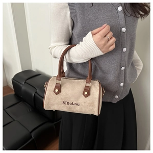 Close-up of vintage Boston bag featuring beige suede material and brown leather handles