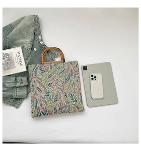 Detail of floral canvas tote bag with natural bamboo handles and thick woven texture