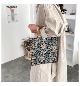Detail of floral tapestry tote bag with vintage bamboo handles on a trench coat model