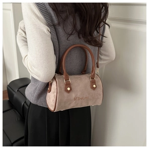 Detail of beige suede Boston bag with brown leather handles and embossed text on side