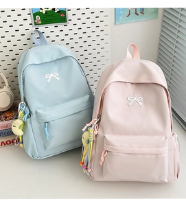 Detail view of light blue and pink nylon backpacks with bow embroidery and moon pendants