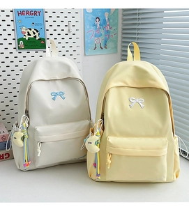 Detail of minimalist school backpacks with bow embroidery and cute moon plush charms