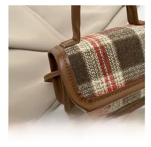 Vue détaillée des coutures précises sur le sac à carreaux vintage avec bordure en cuir