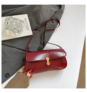 Détail du sac baguette bordeaux vintage avec fermoir doré sur une surface texturée