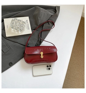 Détail du sac baguette bordeaux en cuir brillant avec fermoir en U doré élégant