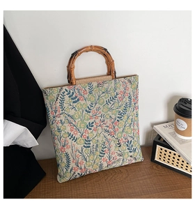 Detail of floral tapestry canvas tote featuring vintage bamboo handles and textured fabric