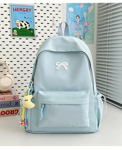 Detail of light blue nylon backpack with white bow embroidery and yellow moon charm