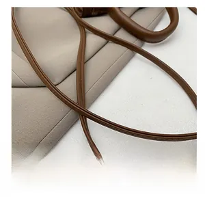 Détail de la bandoulière en cuir marron foncé souple avec des coutures précises sur un sac