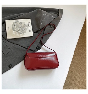 Détail d'un sac à épaule bordeaux brillant avec finition miroir et rabat élégant