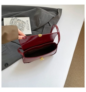 Vue détaillée du sac baguette en cuir verni bordeaux avec compartiment et fermoir doré chic