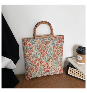 Detailed shot of large floral canvas tote bag featuring unique bamboo round handles on wood