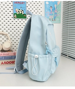 Detail view of light blue nylon backpack side pocket with drawstring and mesh strap