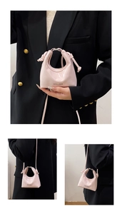 Detail of light pink mini handbag with glossy finish and stylish knot design handles