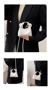 Detail of white glossy patent leather crossbody bag with silver metal ring and logo