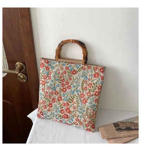Detail of floral canvas tote bag featuring natural bamboo handles and retro embroidery