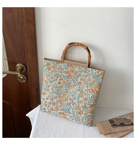 Close-up of floral embroidered canvas tote with natural bamboo handles and woven trim