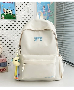 Detail of cream white school backpack with blue bow embroidery and yellow moon plush charm