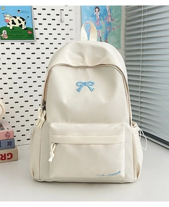 Detailed close-up of cream backpack with blue bow embroidery and side pocket detail
