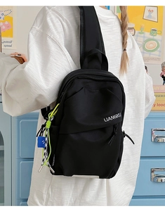 Détail d'un sac de poitrine en nylon noir avec logo et cordon décoratif néon assorti