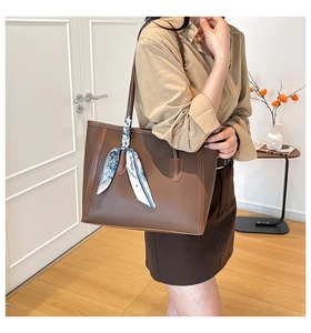 Detail of dark brown lychee leather tote bag with a silk scarf tied on the handle