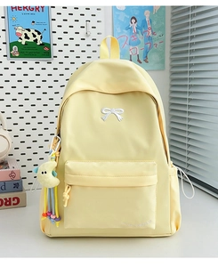 Detail of light yellow nylon backpack featuring bow embroidery and moon plush charm