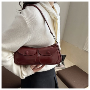 Détail du sac sous le bras rouge brillant avec deux poches frontales et chaîne en métal