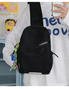 Détail du sac de poitrine en nylon noir avec cordons vert néon et logo blanc
