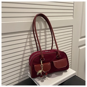 Detailed close-up of velvet baguette bag with cherry charm and glossy pockets