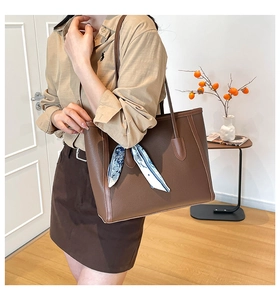 Detail of dark brown litchi pattern leather tote bag with printed silk scarf on handle