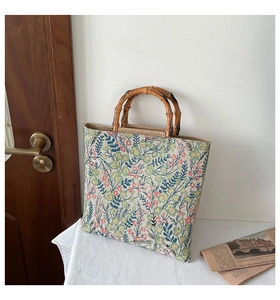 Detail of floral canvas tote bag featuring natural bamboo handles and jacquard fabric