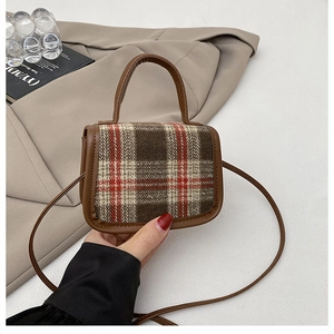 Close-up of small vintage plaid crossbody bag with brown leather trim and top handle