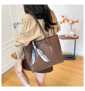 Brown leather tote bag with decorative silk scarf and textured finish for daily commuting