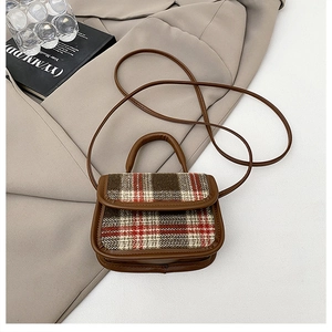 Flat lay of plaid pattern crossbody bag on blazer with book and glass accessory