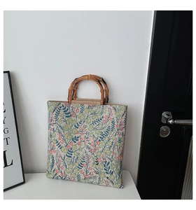 Close-up of floral embroidery on canvas tote bag with vintage bamboo handles