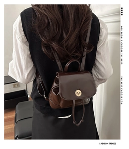 Close-up of vintage dark brown polished leather backpack with gold clasp and drawstring detail