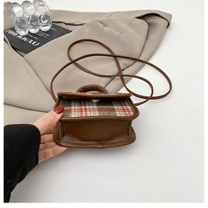 Detailed view of mini vintage crossbody bag with red plaid flap and brown leather strap
