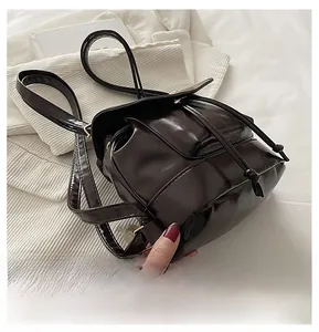 Detail showing high-shine black leather texture and drawstring closure on the mini backpack