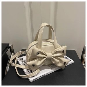 Détail d'un sac à main beige avec nœud et clous étoilés posé sur une chaise chic